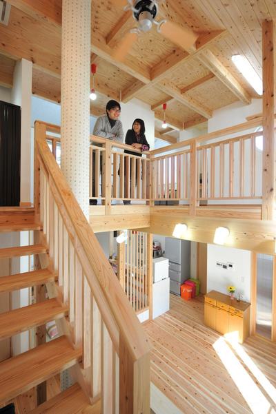 LDKは2階へと続く階段も含め、高い吹抜けが開放的です。一見、大きな柱かと思いきや実はOMソーラーのダクトです。かわいい木の模様のクロスを張り、空間に馴染んでいます。