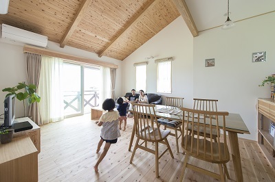 勾配のある天井や床など、小国杉の強さと美しさが随所に息づく広々としたリビング。リビングの一面を調湿・消臭機能に長けた珪藻土。淡いピンクの塗壁に。