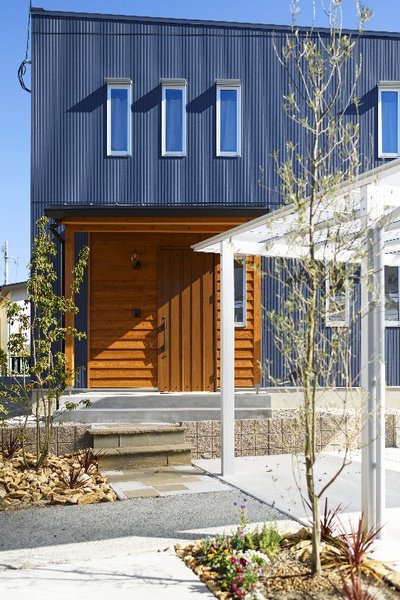 外観は爽やかなネイビーブルー。玄関ドアの周りだけ無垢板貼りにしてナチュラルな雰囲気に。