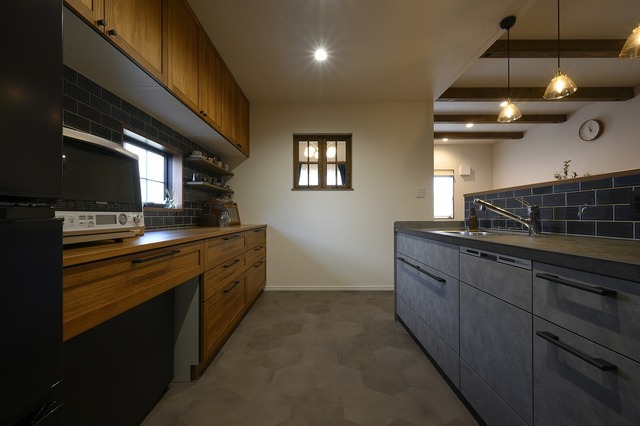 6帖のキッチンは、床を6角タイルにしリビングダイニングと貼り分けました。家電の色と合うように、キッチンはダークトーンに。そして収納は無垢を使っています。
飾り棚には、お施主様お気に入りのカップを並べ、カフェのような雰囲気です。
室内窓からは、ピアノスペースを見ることができます。