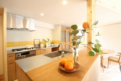 壁は黄色のタイルがアクセントに。LDKのセンターに配置したオープンキッチン。