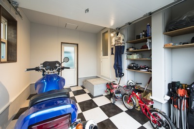 白い輸入シャッターとチェッカーフラッグ柄の床。ご主人の要望が盛り込まれた夢の空間の主役はＨＯＮＤＡ　ＣＢ1000スーパーフォア。
7帖程の広さがあるのでバイクメンテナンススペースの他に工具やゴルフバック、子供さんの自転車もゆっくり収納できます。そしてキッチンパントリーや車庫からの出入りもできます。
ご入居前は住まいとは別の場所に専用のガレージを借りてお休みの日に通っていらっしゃたそうですが、これからは好きなときに愛車のお手入れをすることができます。