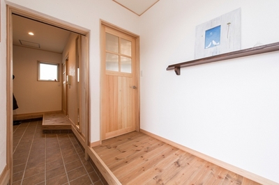 ドアを開くと横長に広がる玄関。奥には家族専用のシューズクロークとリビングへの出入り口が伸びている。