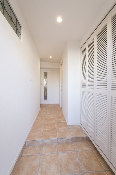 玄関収納は通気がよいルーバー扉に。玄関のテラコッタタイルを廊下まで続けさせ、広く見せています。 玄関収納は通気がよいルーバー扉に。玄関のテラコッタタイルを廊下まで続けさせ、広く見せています。