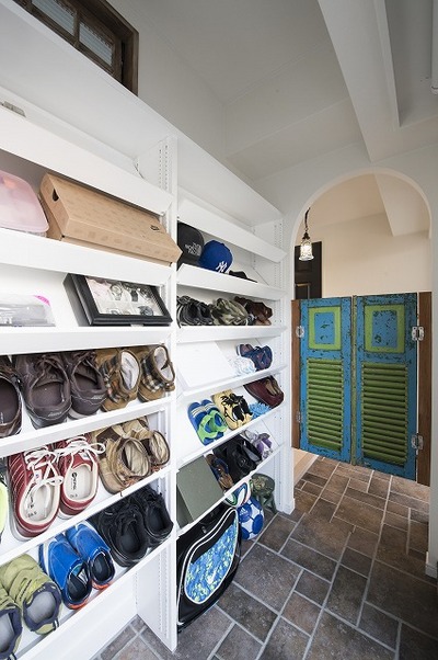 玄関は、デザイン貼りのタイルと味わいのある無垢ドアがお出迎え。
玄関横にはシューズインクロークを設けました。棚をななめに施工することで、最小限の広さで収納力を確保しました。入口のアーチとアンティークドアがアクセントになっています。