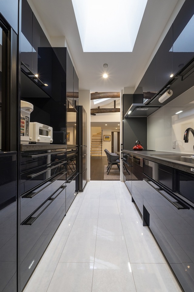 つややかなダークブルーで統一された洗練されたキッチンスペース。生活感のある家電がリビング側から見えない、独立型のレイアウトをセレクト。奥側で洗面・バスルームとつながる便利な動線を設けている つややかなダークブルーで統一された洗練されたキッチンスペース。生活感のある家電がリビング側から見えない、独立型のレイアウトをセレクト。奥側で洗面・バスルームとつながる便利な動線を設けている