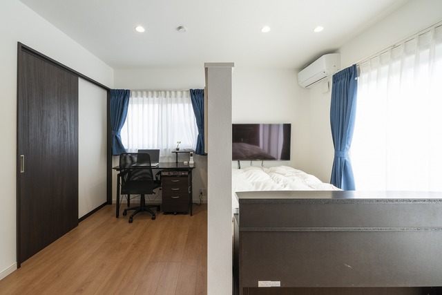 ご夫婦それぞれの寝室を確保して、自分時間を大切にできる設計に。オンとオフで気持ちが切り替えやすいように、デスクスペースとベッドスペースに仕切りを設けた。壁面には大きなタンスがまるごと収まる収納を設け、スッキリとした印象に ご夫婦それぞれの寝室を確保して、自分時間を大切にできる設計に。オンとオフで気持ちが切り替えやすいように、デスクスペースとベッドスペースに仕切りを設けた。壁面には大きなタンスがまるごと収まる収納を設け、スッキリとした印象に