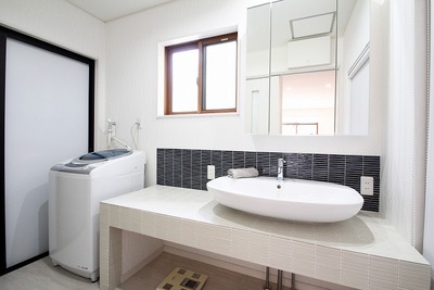 お父様の作業場だった土間部分を浴室、洗面脱衣室へ。
シックな色合いのタイルで仕上げた広いカウンターに楕円のボウルがおしゃれな空間。