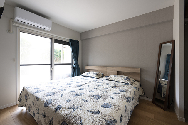 グレーのアクセントクロス、ブルーのベットカバーとカーテン、シンプルで落ち着いた寝室。
そして限られたスペースに壁掛けのテレビを設置。