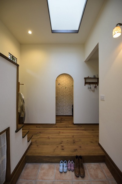 天窓から自然光が差し込む明るい玄関。正面の収納スペースへの入り口にはアールをつけて優しい表情に。