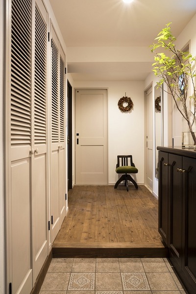 クラシカルなタイルと靴箱のデザインを生かした玄関。左側に大容量の収納を設置。