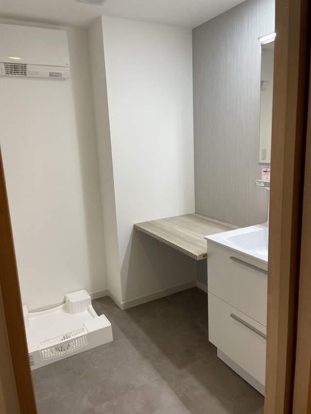 洗面台の横にカウンターを設けました。椅子を置けばゆっくりと腰掛けることができます。
洗濯パンも640角のサイズへ変更し、高圧洗浄しやすいように嵩上げタイプにしました。
洗面所には暖房も設置し、浴室との寒暖差をなくしています。