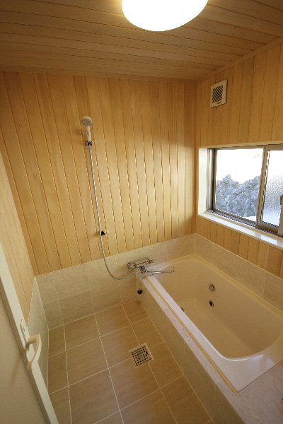 床、浴槽の廻りはタイル貼り、壁は一面、無垢のヒバ板貼りの浴室に